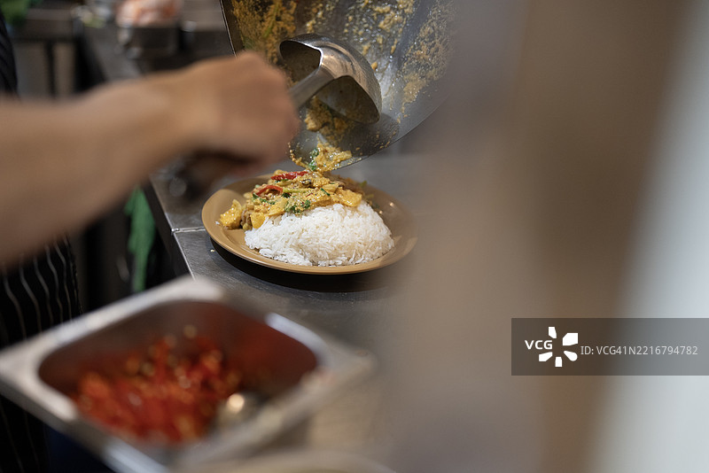 亚洲厨师在专业厨房炉灶上用热锅炒菜，火焰熊熊。图片素材