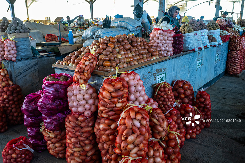 在乌兹别克斯坦塔什干的市场摊位上展示的大量洋葱和土豆图片素材