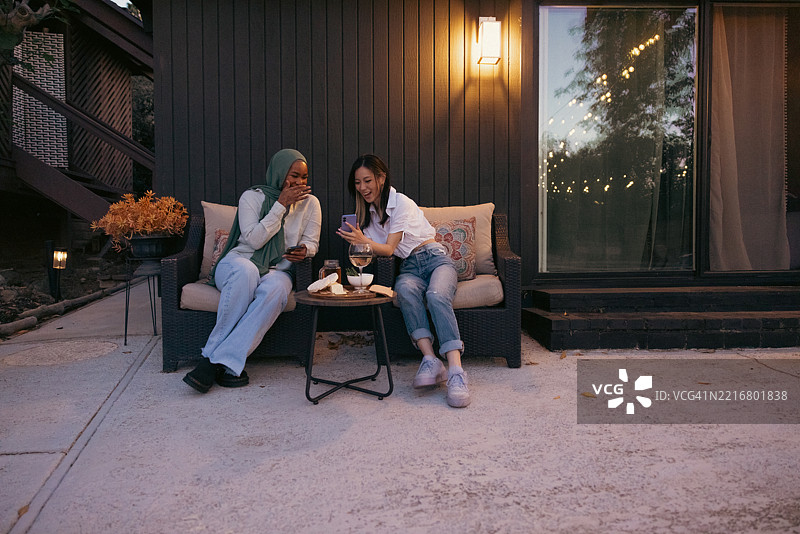两位女性在家中的露台上放松，享用晚餐前的小吃和饮料图片素材