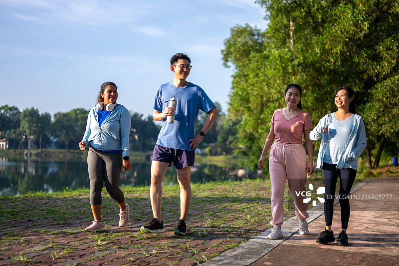 一群亚洲男女在公园湖边跑步和慢跑图片素材