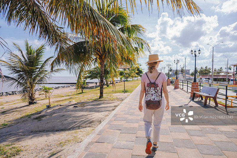 在圭亚那乔治城的海堤上散步的女人图片素材