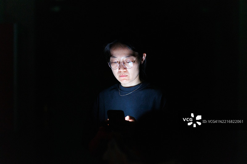 一位亚洲女性在深夜使用手机图片素材