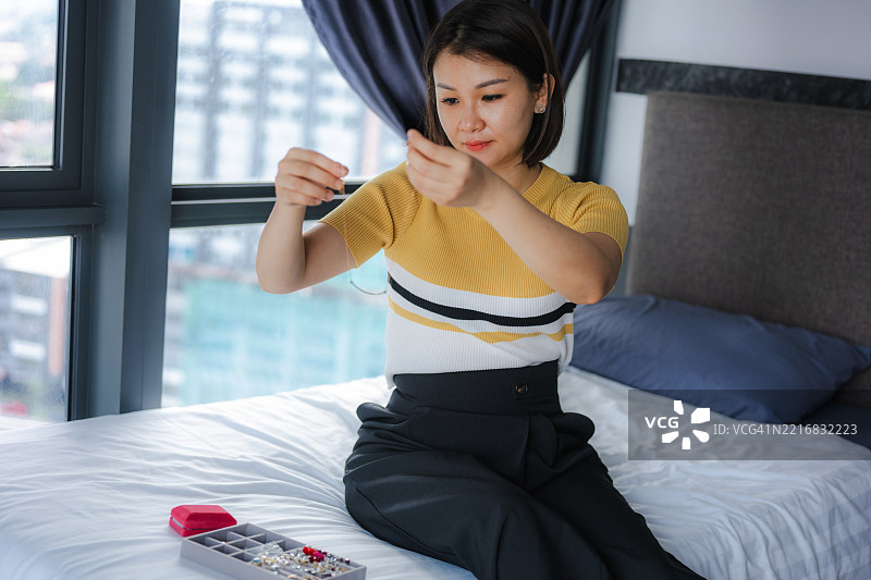 一位美丽的女性在出门前挑选项链。图片素材