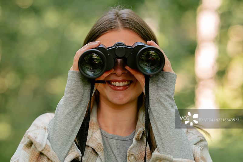年轻女性在森林中使用望远镜探索自然图片素材