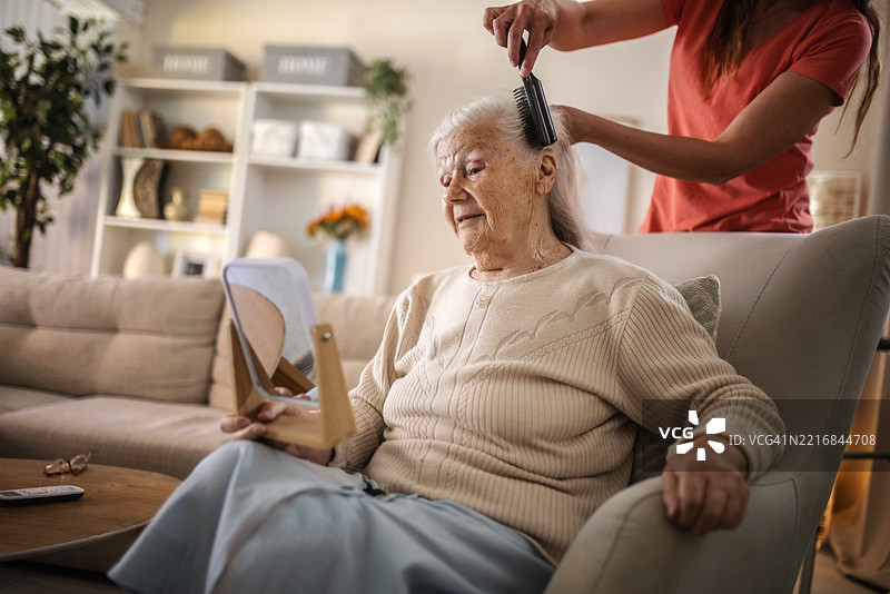 女儿在家里照顾年迈的母亲，为她梳头发图片素材