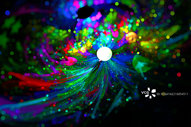 发光的霓虹涂料漩涡与宇宙飞溅效果。抽象的霓虹涂料漩涡，伴随着发光颗粒，像是在黑暗背景上绽放的宇宙色彩爆炸。图片素材