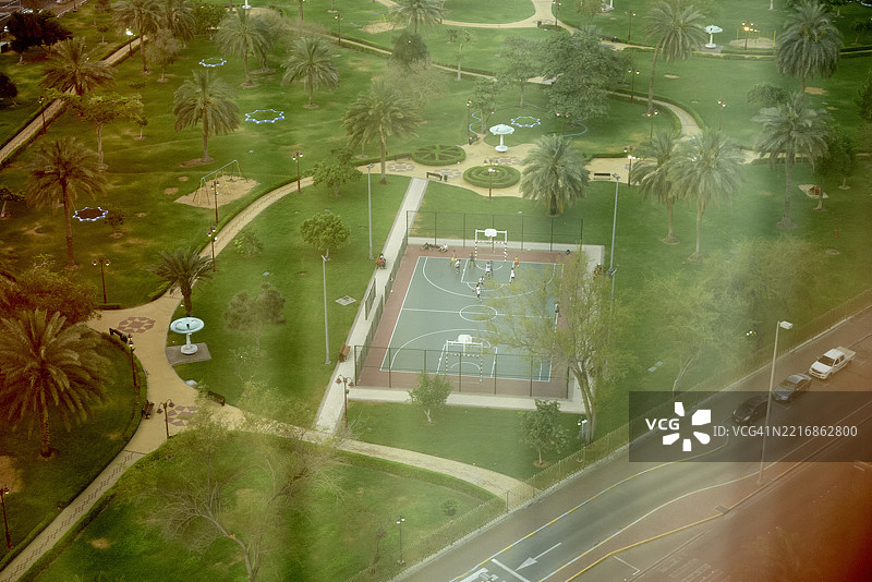 阿布扎比，阿联酋的绿意盎然的公园鸟瞰图，公园内有棕榈树和篮球场。图片素材