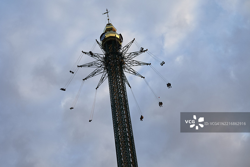 高耸的游乐园设施，游客在多云的天空中高高摆动。奥地利图片素材
