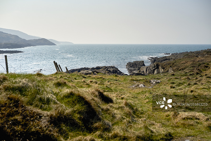 爱尔兰西海岸的海岸风景，草坡、岩石海岸和宁静的蓝色海洋在晴朗的天空下。图片素材