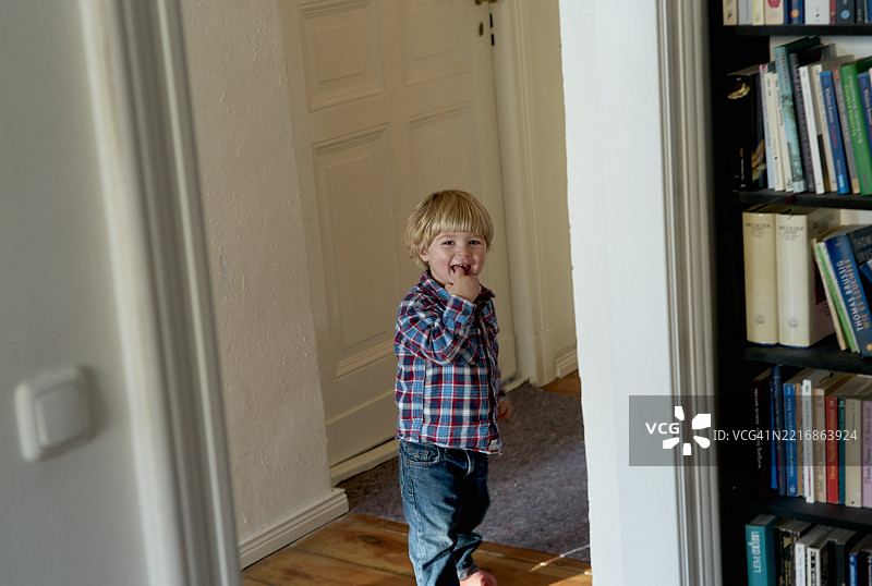 穿着格子衬衫的小孩在书架和木地板的房间里走动图片素材