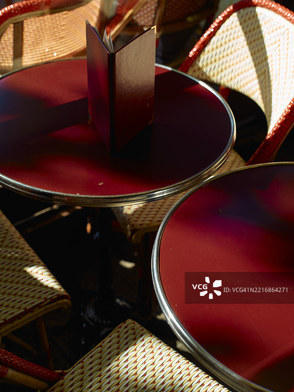 阳光照耀下的红色咖啡桌，周围紧密排列着编织的藤椅。图片素材