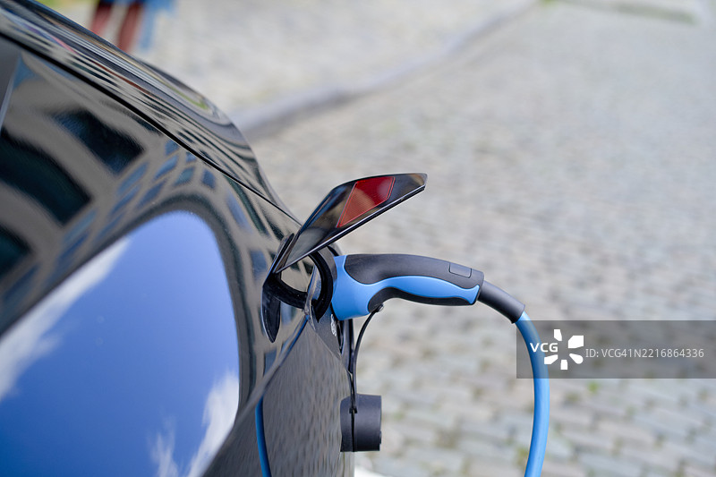 电动车在鹅卵石街道上充电，映照在光滑的蓝色表面上图片素材