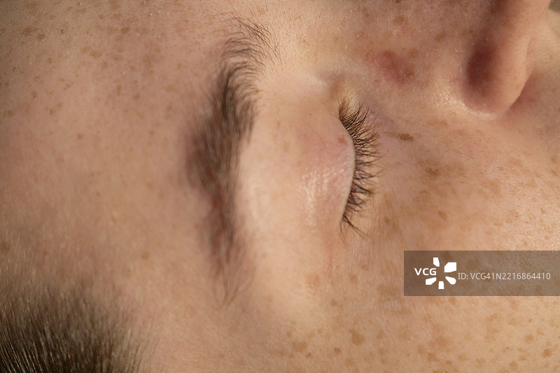 西班牙马拉加一位女性的特写，脸上有雀斑，闭着眼睛，睫毛清晰可见。图片素材