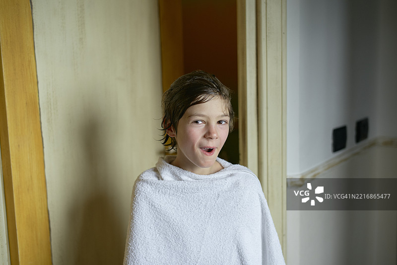 年轻男孩在意大利西西里岛的酒店房间里裹着白色毛巾度假。图片素材