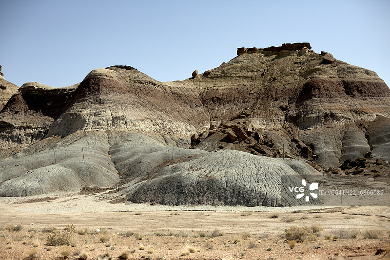 干旱的沙漠景观，层叠的岩石在晴朗的蓝天下。美国公路旅行图片素材