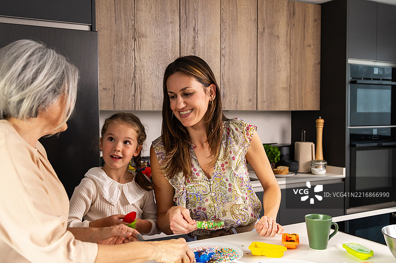 三代女性在现代厨房一起烘焙图片素材