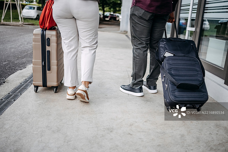 商务人士一起出差，走在人行道上，手提行李，仅显示腿部。图片素材