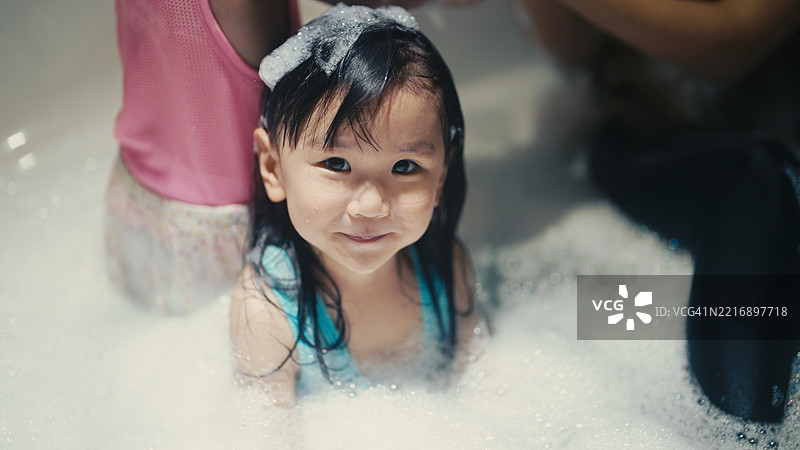 浴缸里的肥皂泡与姐姐。图片素材