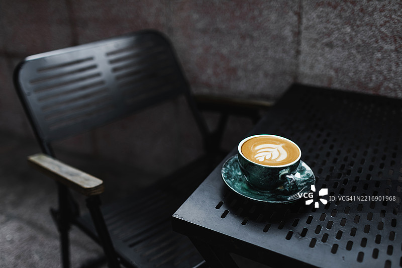 舒适的户外咖啡馆场景，特色是时尚绿色杯中的拿铁咖啡图片素材
