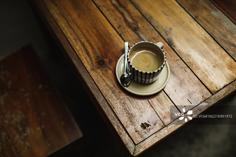 木桌上的一杯黑咖啡或浓缩咖啡。低调，俯视角度。图片素材