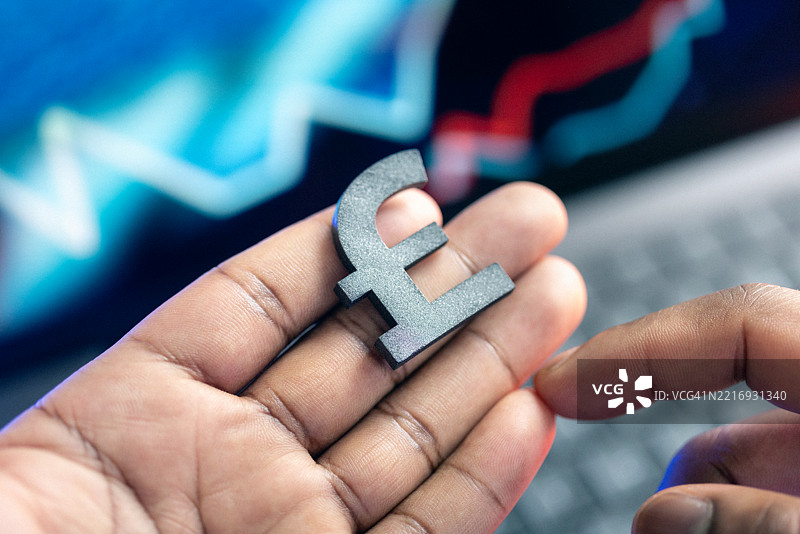 手握英镑符号的特写，背景模糊图片素材