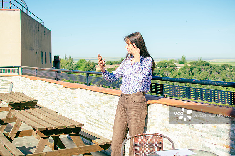 在风景如画的屋顶露台上进行视频通话的女商人图片素材