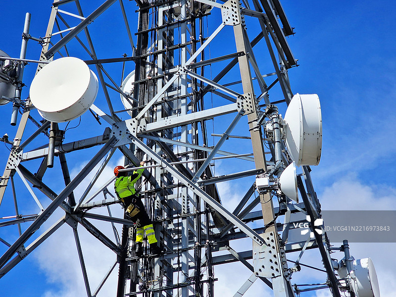 在大型钢铁塔上工作的工程师公用设施工作人员，使用无线电链接。图片素材