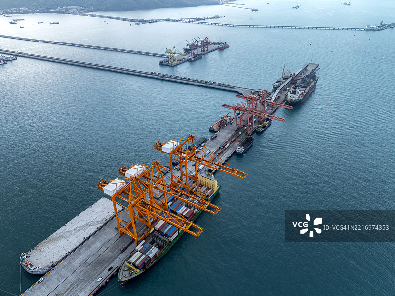 鸟瞰图，起重机在中型港口的仓库中将集装箱装载到货船上。商业贸易物流和运输，进出口通过集装箱货船。图片素材