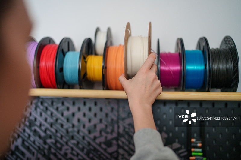 女性从架子上取下3D打印用的线轴图片素材