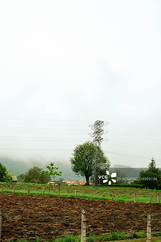 电力塔耸立在雾气弥漫的农田上图片素材