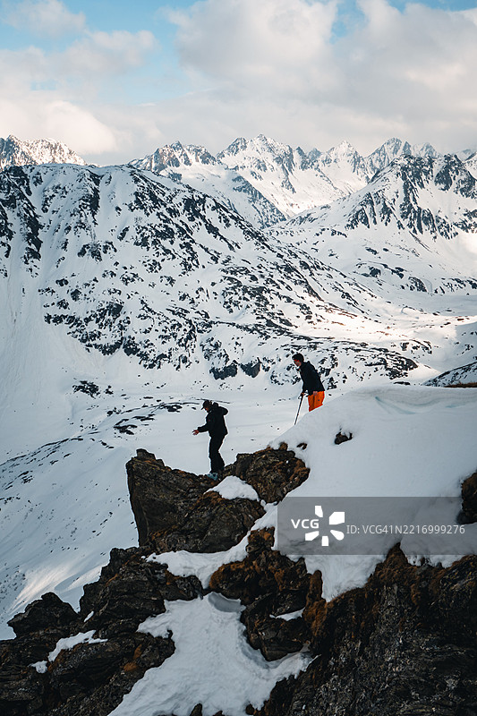 朋友们在冰川山脉的岩石山脊上攀爬图片素材