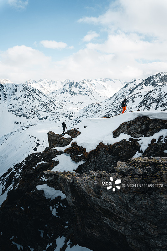 朋友们在冰川山脉的岩石山脊上攀爬图片素材