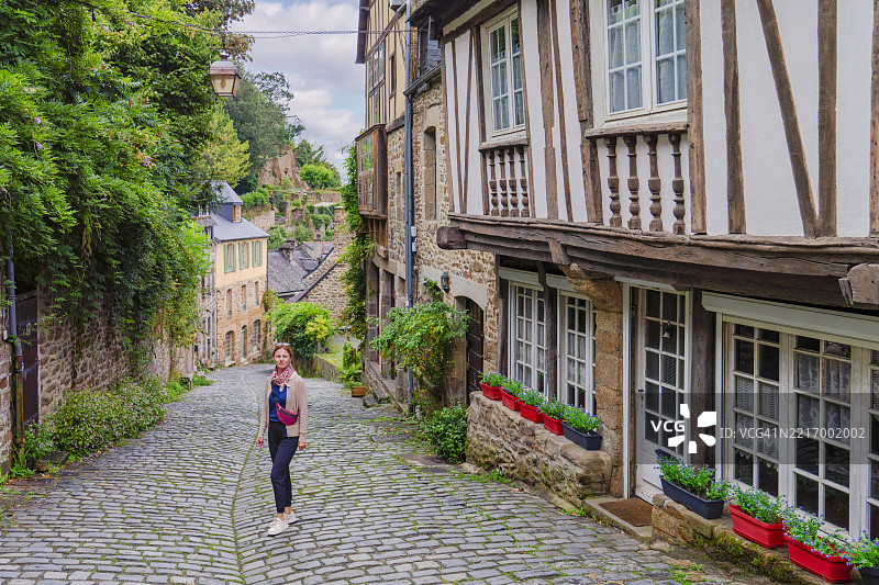 一位女性在法国布列塔尼的迪南中世纪小镇探险。图片素材