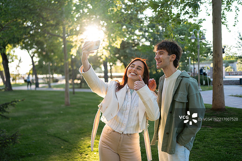 朋友们在阳光明媚的公园里微笑着自拍图片素材