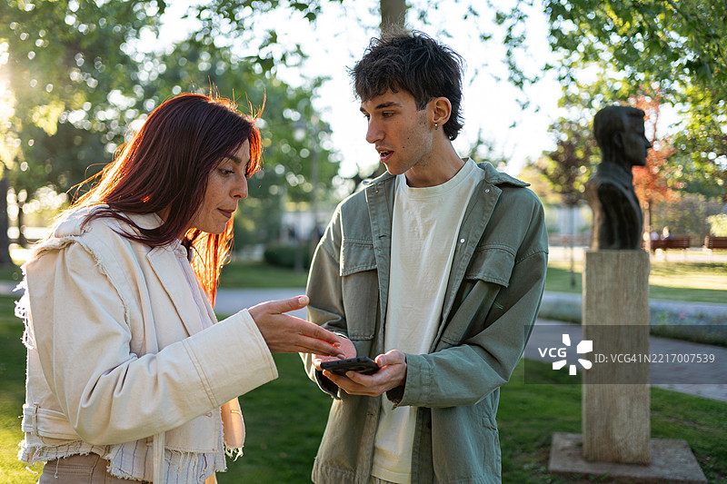 两个人在使用手机时讨论一个问题图片素材