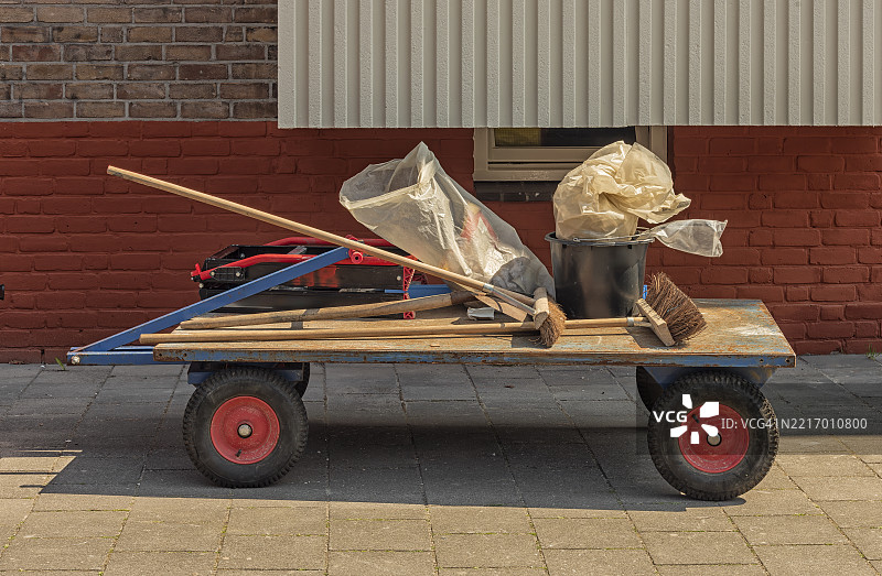 装满扫帚和一个黑色塑料袋的手推车图片素材