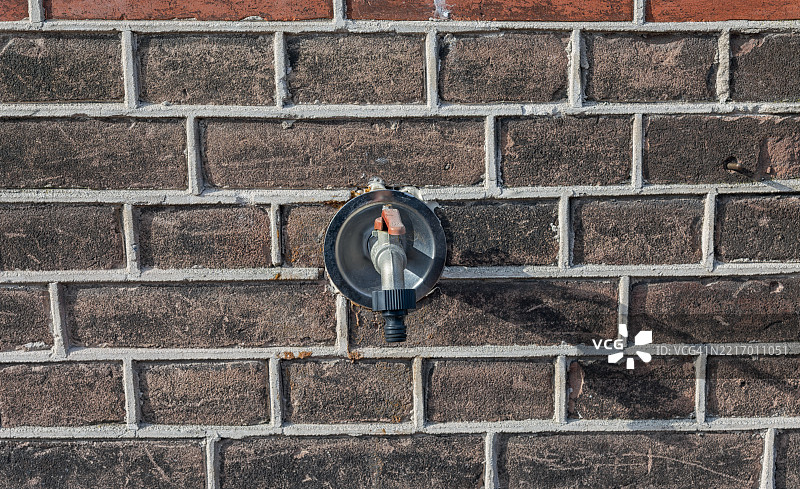 户外水龙头安装在石墙上图片素材