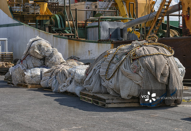 渔网和渔具整齐地堆放在码头的木托盘上。图片素材