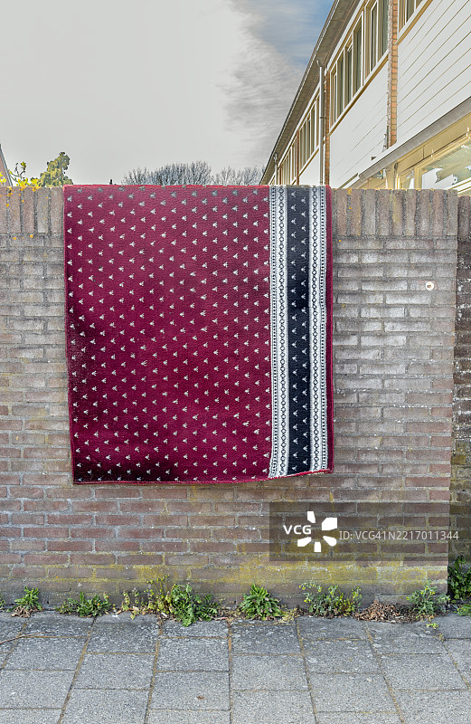 红地毯上有各种图案，铺在住宅房屋外的石头上。图片素材