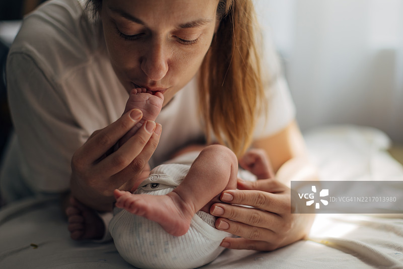 母亲亲吻她新生女儿的脚丫图片素材