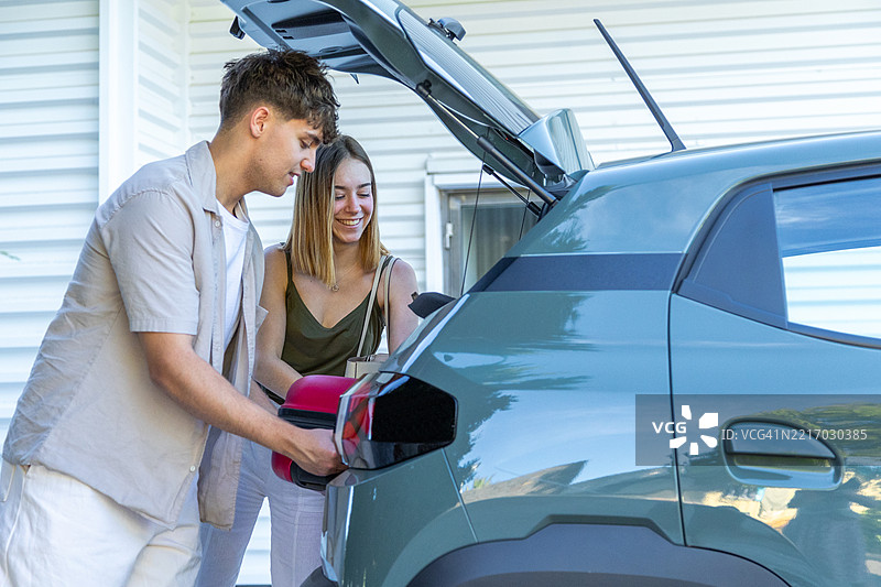 年轻情侣在公路旅行前将行李装入汽车后备箱图片素材
