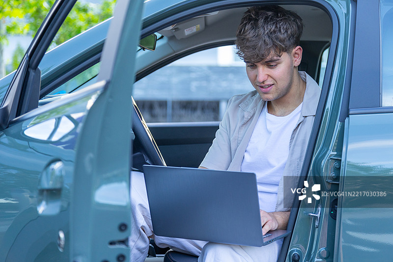 年轻商人在车内使用笔记本电脑工作图片素材