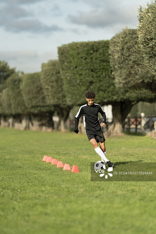 少年男孩在锥形标志间练习足球图片素材