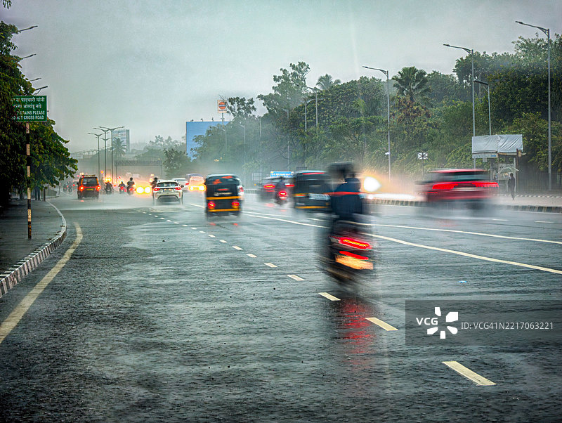 在印度纳维孟买，车辆在雨水浸湿的道路上小心行驶，正值强降雨季节。该图像反映了城市生活的节奏，在印度雨季的低能见度和潮湿条件下。图片素材