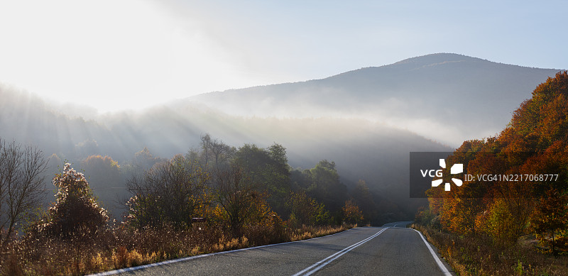 蜿蜒的道路穿过生机勃勃的秋季山丘图片素材