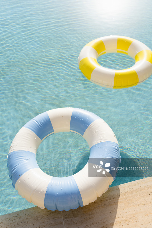 不同颜色的充气圈漂浮在游泳池中图片素材