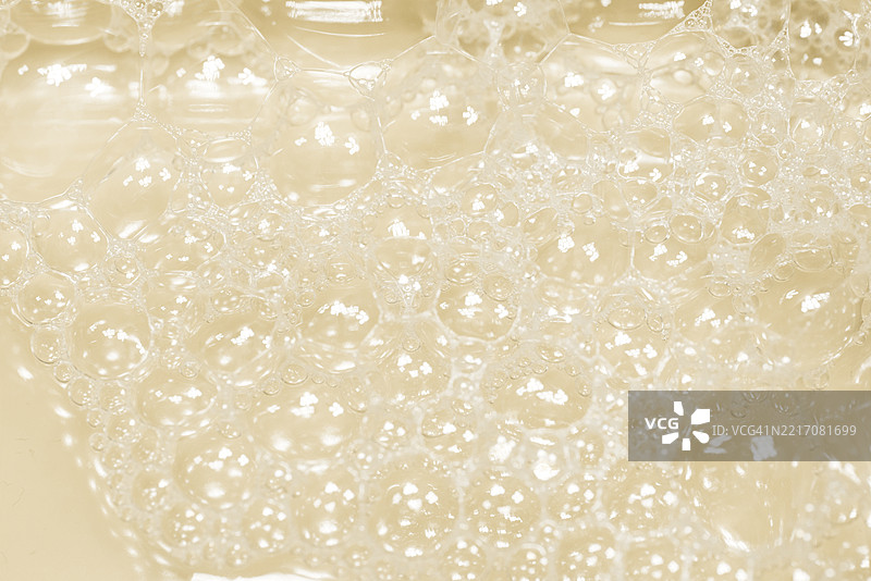 柔和米色背景下闪烁的透明肥皂泡特写图片素材