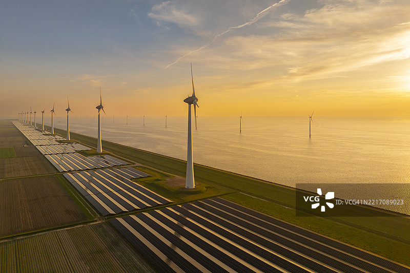 湖岸上的风力涡轮机和太阳能电池板图片素材