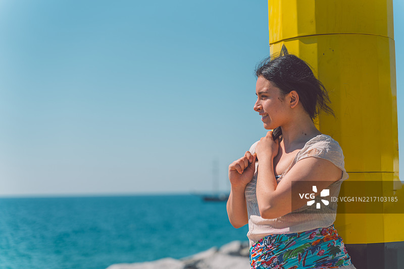 年轻女性在黄色柱子旁享受巴塞罗那的海滩生活图片素材