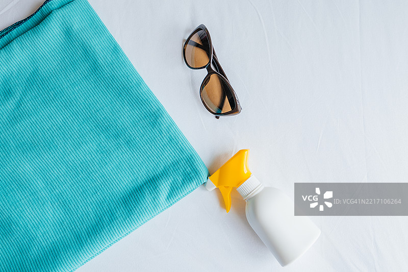 沙滩装备、毛巾、防晒霜和太阳镜放在白色床单上图片素材